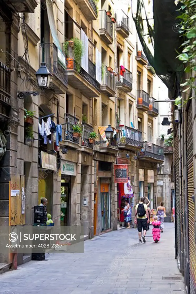Barcelona, Catalonia, Spain, girl in traditional clothingwalks down a narrow street lined with balconies in the Gothic Quarter.