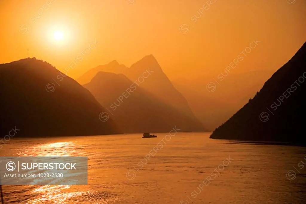 China, Yangtze River, sunset over river, river boats in distance.