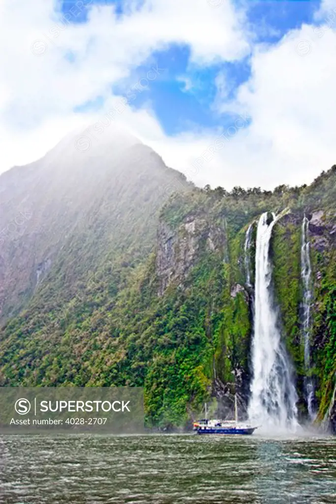 Milford Sound, Fiordland National Park, New Zealand, Sterling Falls drops 151m into the Sound as a cruise ship is sprayed with the mist