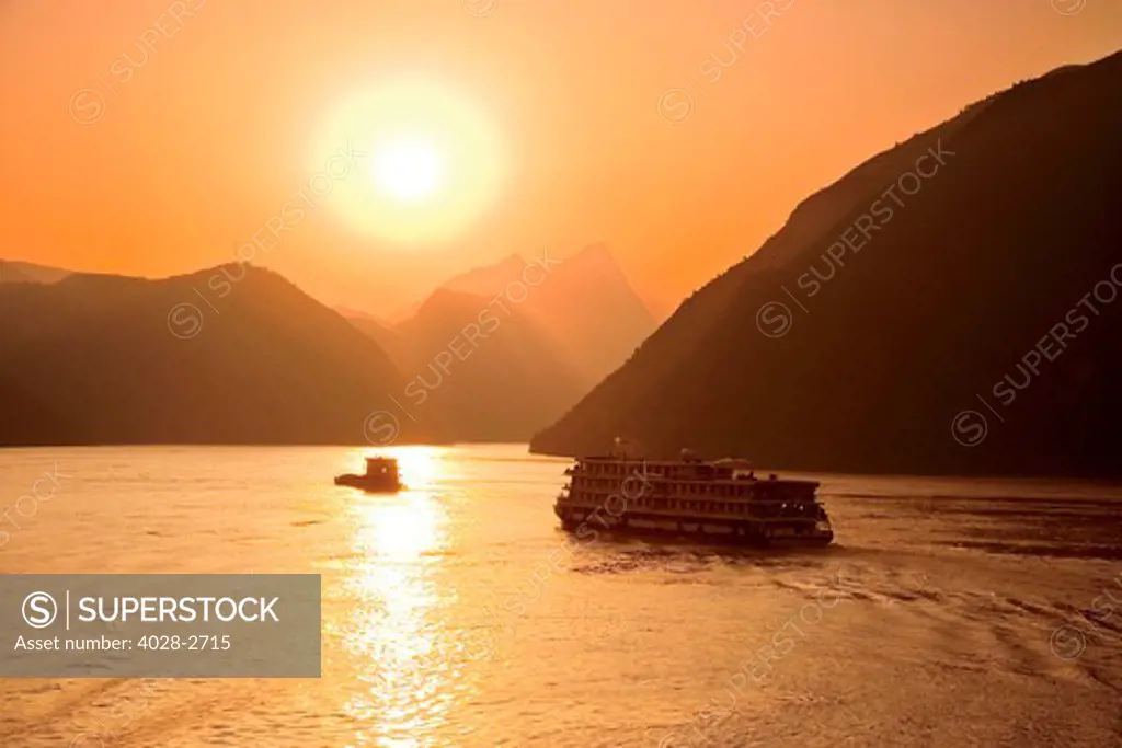 China, Yangtze River, sunset over river, river boats in distance.