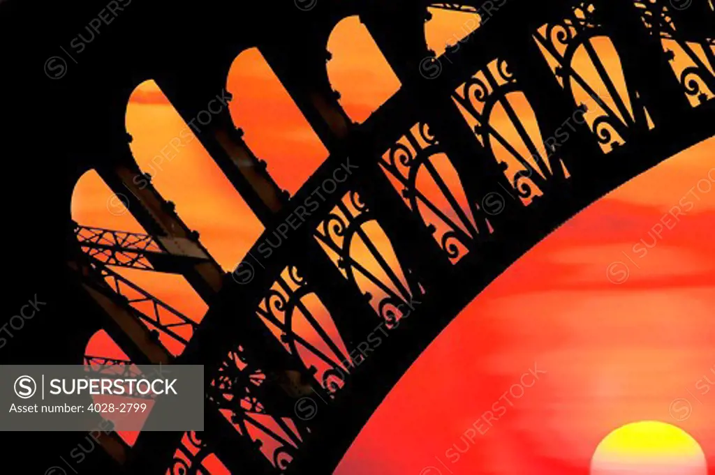 France, Paris, Detail of an Eiffel Tower (La Tour Eiffel) arch from underneath the structure illuminated at by the setting sun.