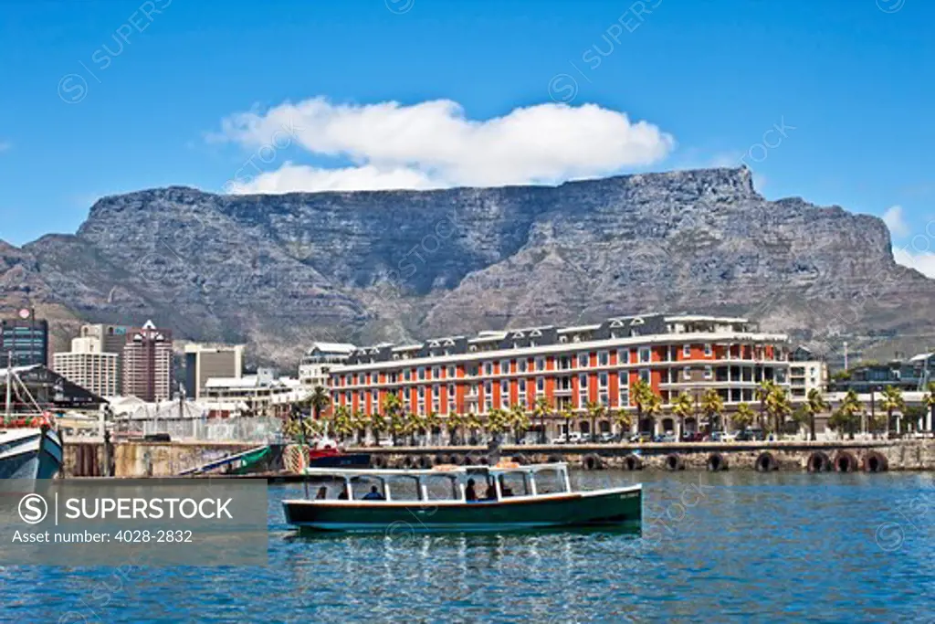 Cape Town, South Africa, A water taxi sails by the The Victoria and Albert waterfront with Table Mountain in the background