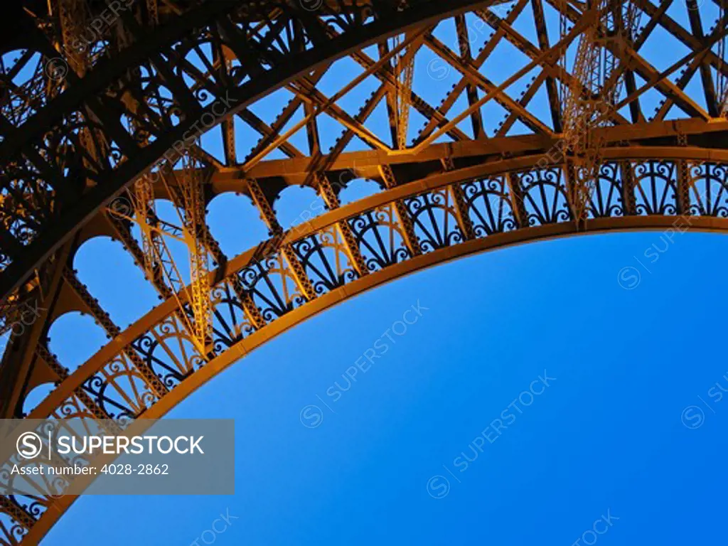 France, Paris, Detail of an Eiffel Tower (La Tour Eiffel) arch from underneath with a  blue sky showing through