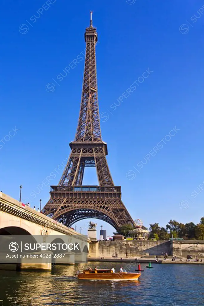 Paris, ile-de-France, France, a small boat passes underneath the Pont D'Lena bridge on the Seine River by the Eiffel Tower (Tour Eiffel)