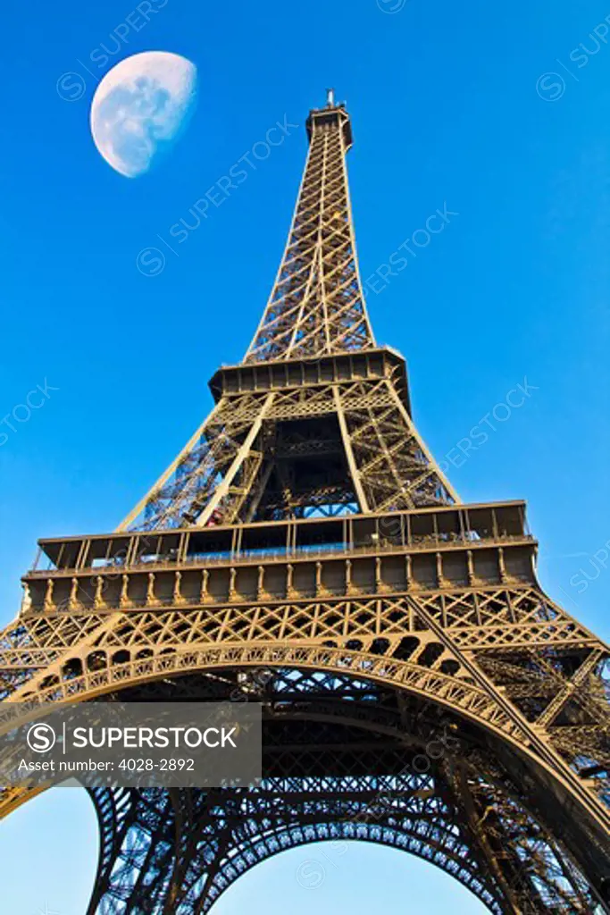 France, Paris, Detail of an Eiffel Tower (La Tour Eiffel) arch from underneath the base of the structure with a blue day moon