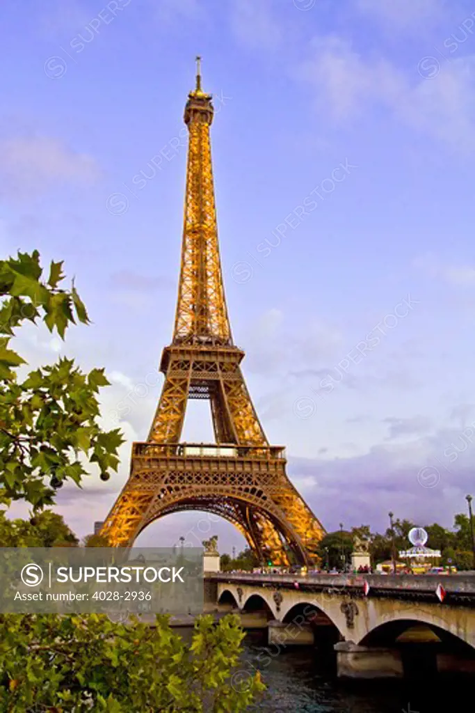 Paris, ile-de-France, France, the illuminated Eiffel Tower (Tour Eiffel) with the Pont D'Lena bridge over the Seine River in the evening