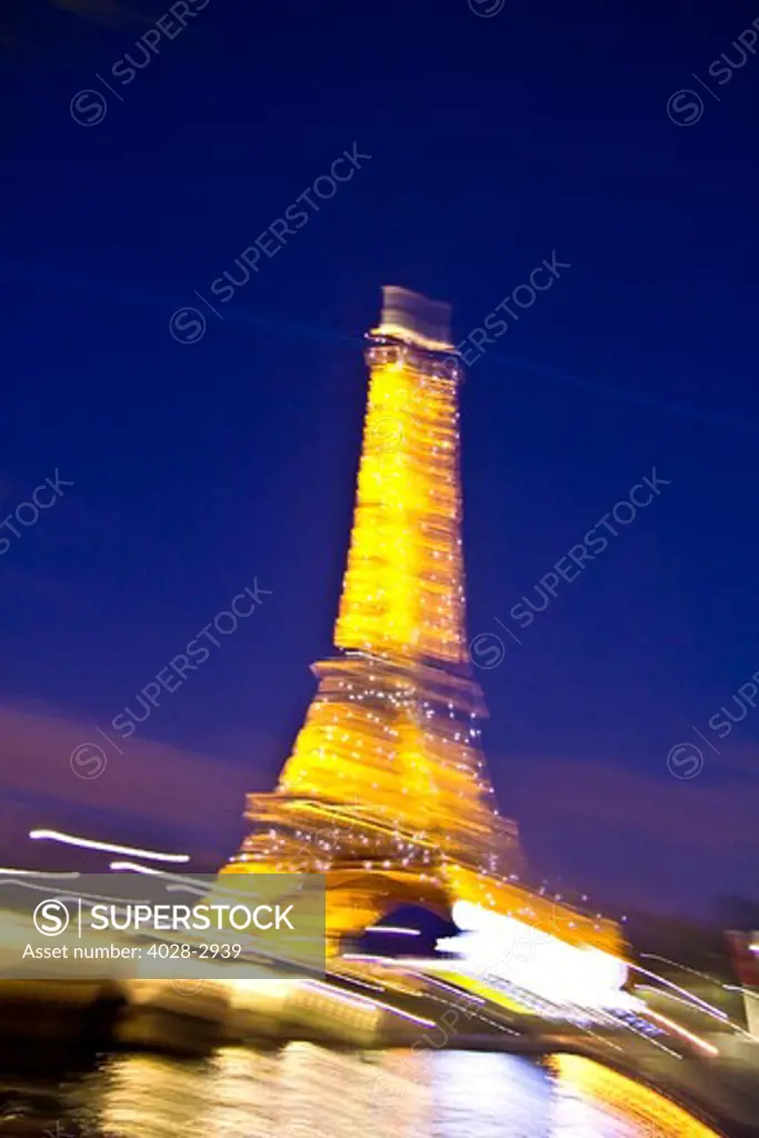 Paris, ile-de-France, France, the illuminated Eiffel Tower (Tour Eiffel) with the Pont D'Lena bridge over the Seine River shot with motion blur at night