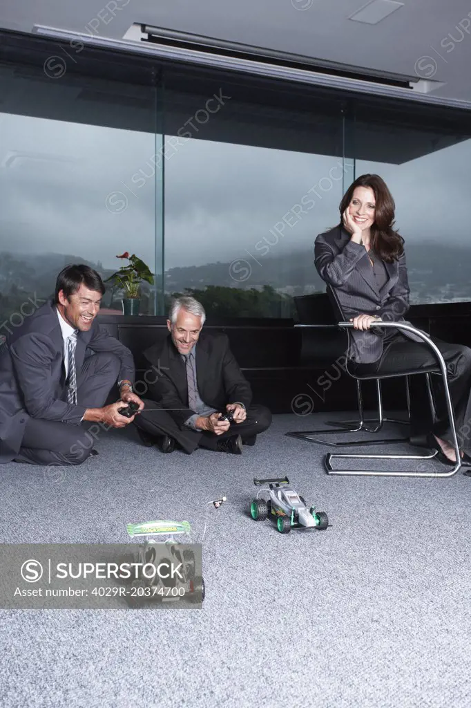 Businessmen playing with toy automobiles