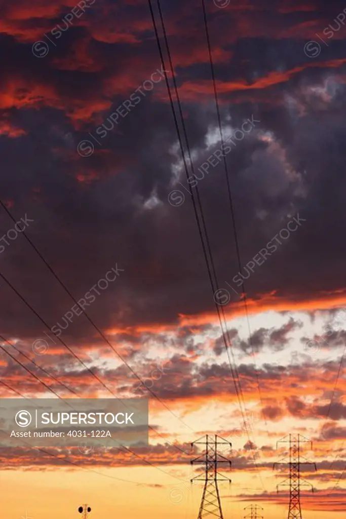 Transmission towers silhouetted against a dramatic sunset sky. Stanislaus county, California, USA