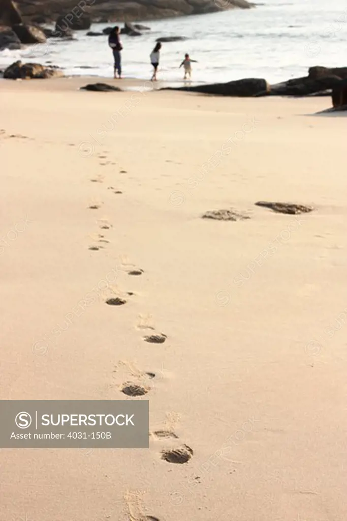 Footprints with a woman and her children in the background on the beach, Kinmen County, Taiwan