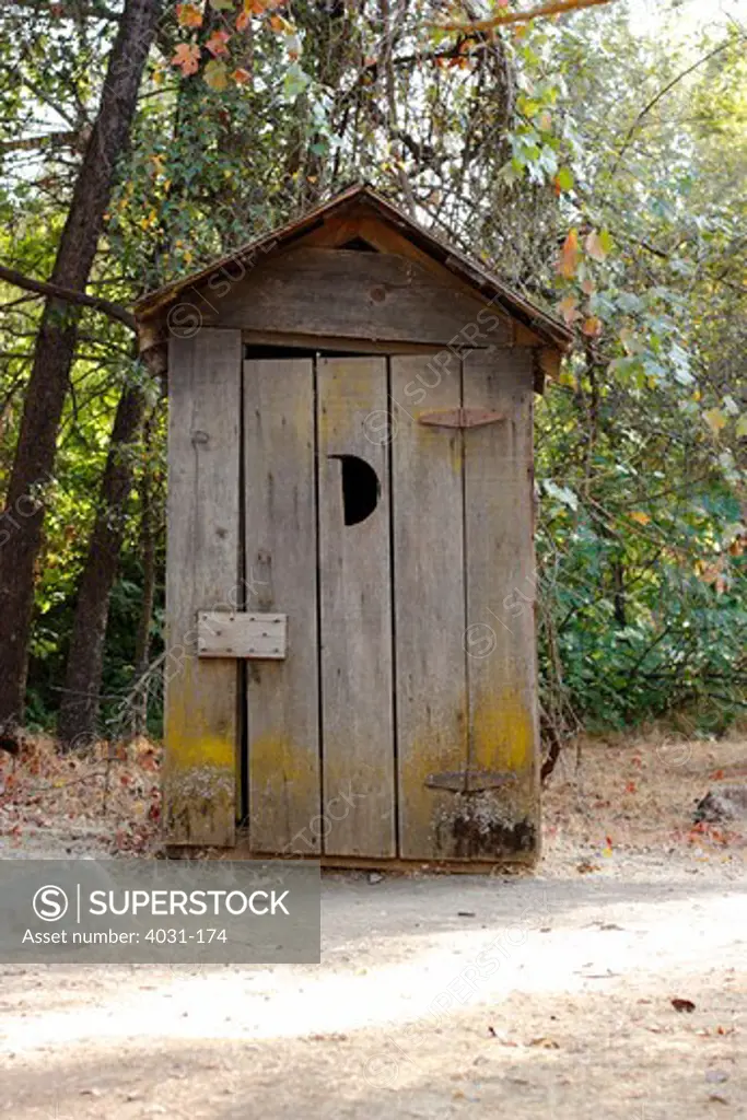 Old outhouse with a crescent moon shaped hole on the door in a park, Columbia State Historic Park, Columbia, Tuolumne County, California, USA