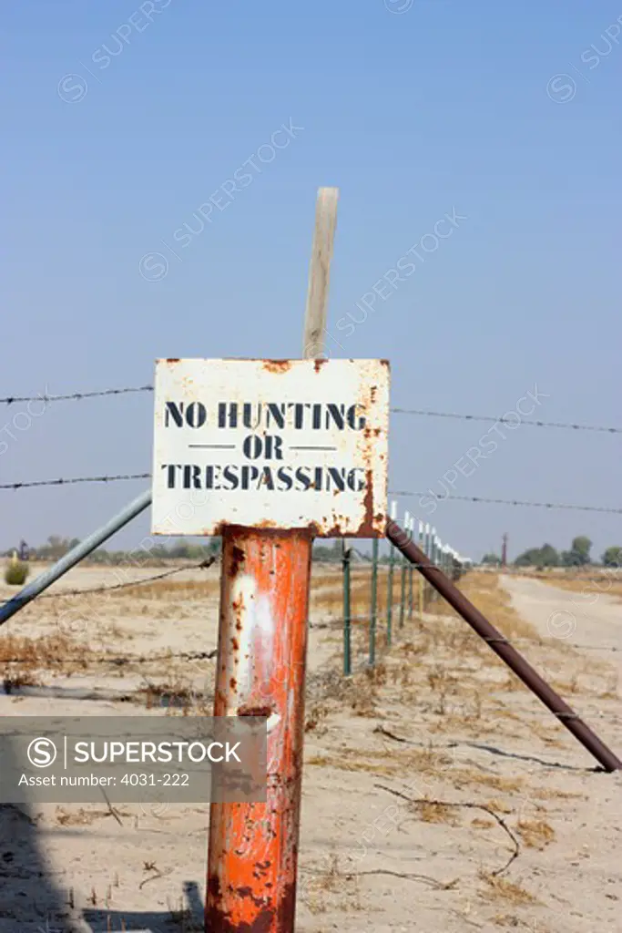 USA, California, Kern county, No Hunting or Trespassing sign in front of barbwire fences marking property lines