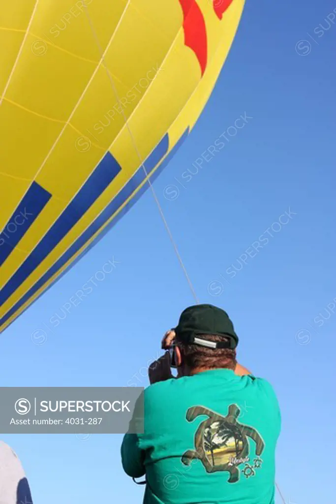 USA, California, Ripon, Spectator photographing hot air balloon at Color the Skies Hot Air Balloon Festival