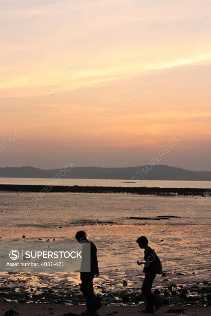 Taiwan, Kinmen County, Jincheng, Couple walking past oyster beds at sunset