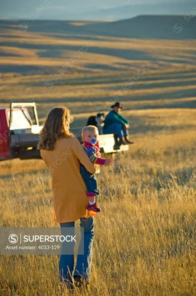 Family with a dog and a pick-up truck in a field, Montana, USA
