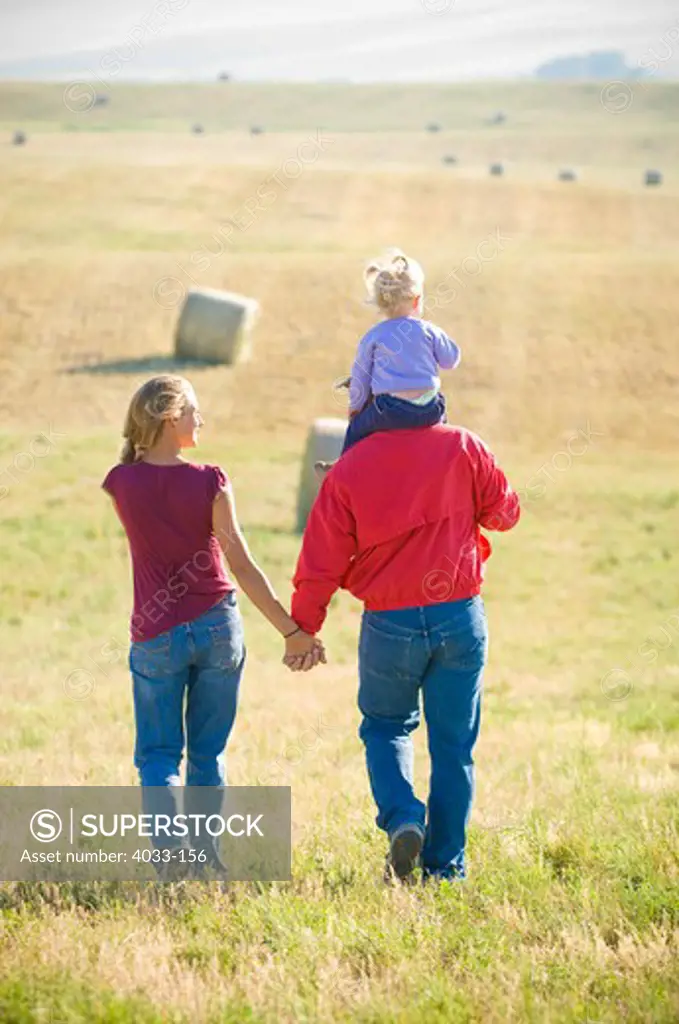 Young couple with their daughter walking in a mowed field, Bozeman, Gallatin County, Montana, USA