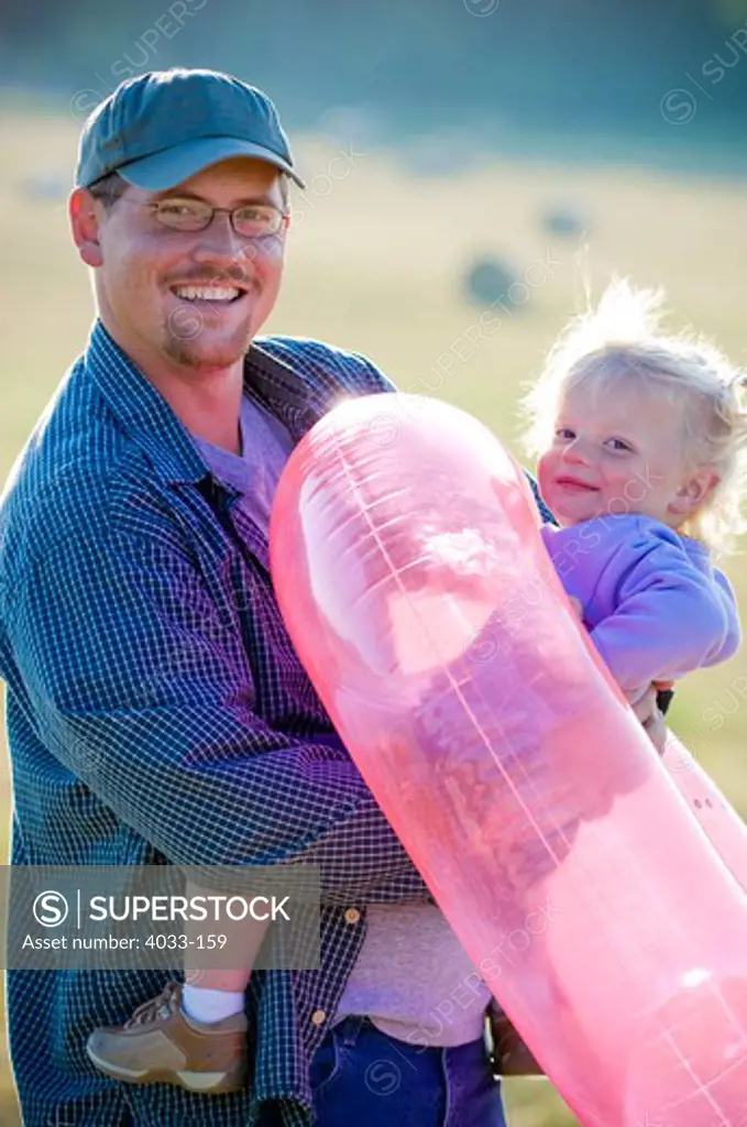 Young man carrying his daughter with an inner tube, Bozeman, Gallatin County, Montana, USA
