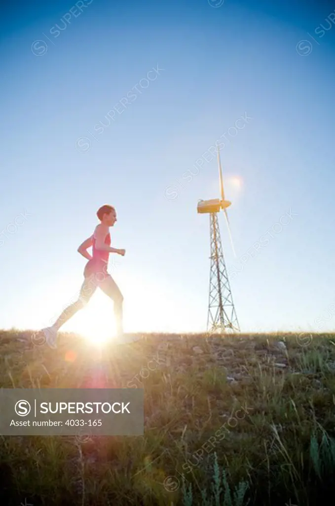 Low angle view of a young woman running by a windmill, Bozeman, Gallatin County, Montana, USA