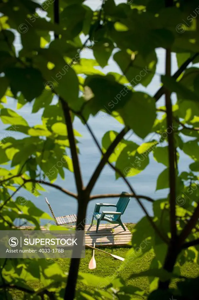 Two chairs and oars at the lakeside viewed from the branches of a tree, Ithaca, New York State, USA