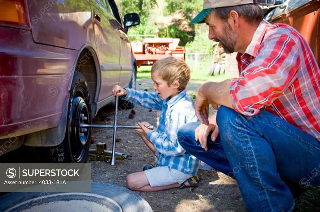 Man watching his son changing the flat tire, Bozeman, Gallatin County, Montana, USA