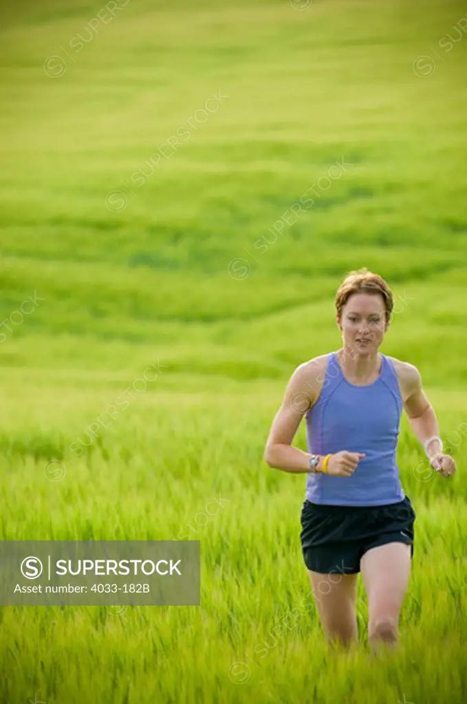 Woman running in a wheat field, Bozeman, Gallatin County, Montana, USA