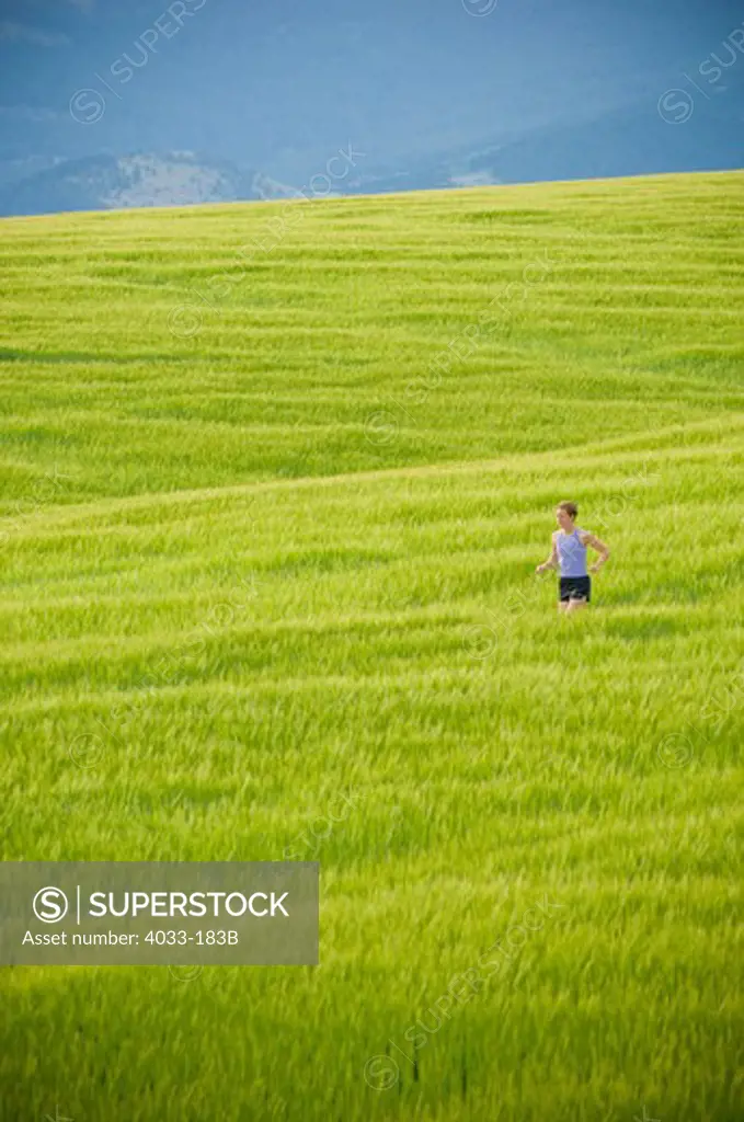 Woman running in a wheat field, Bozeman, Gallatin County, Montana, USA