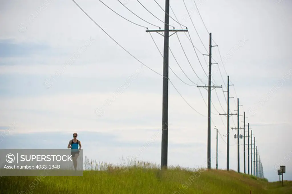 Woman running beneath power lines, Bozeman, Gallatin County, Montana, USA