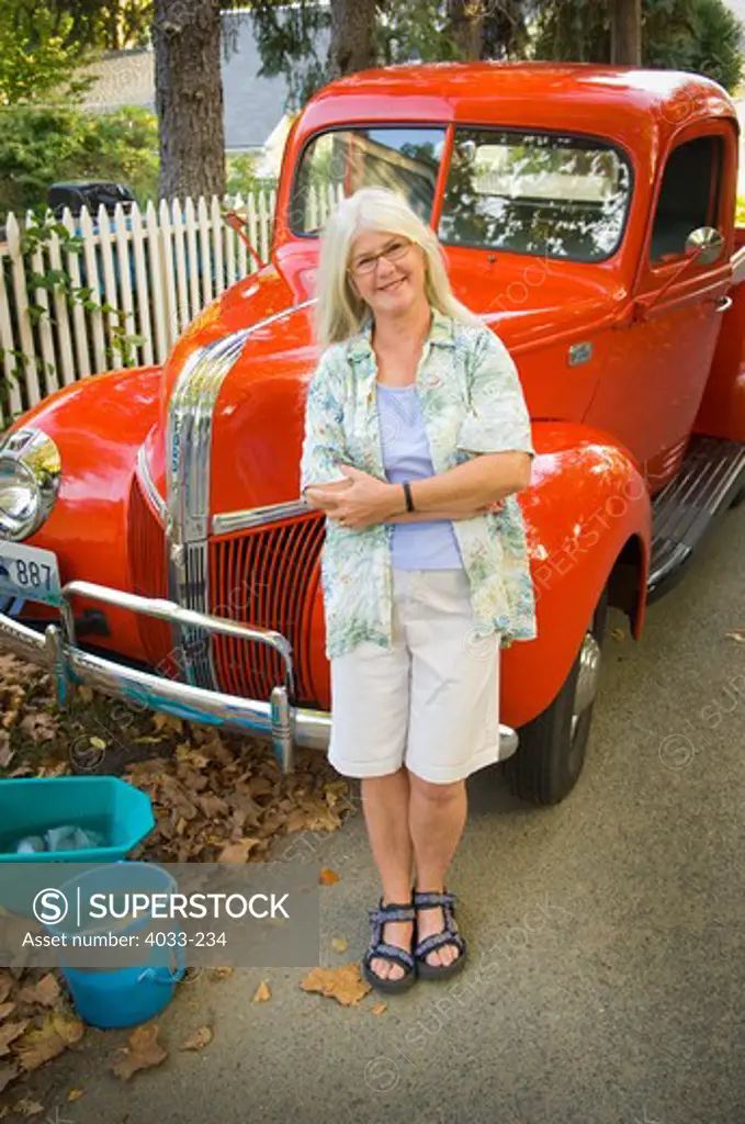 Mature woman leaning against a vintage pick-up truck and smiling, Jamestown, Rhode Island, USA