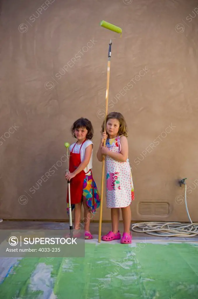 Two girls holding paint rollers, La Jolla, San Diego County, California, USA