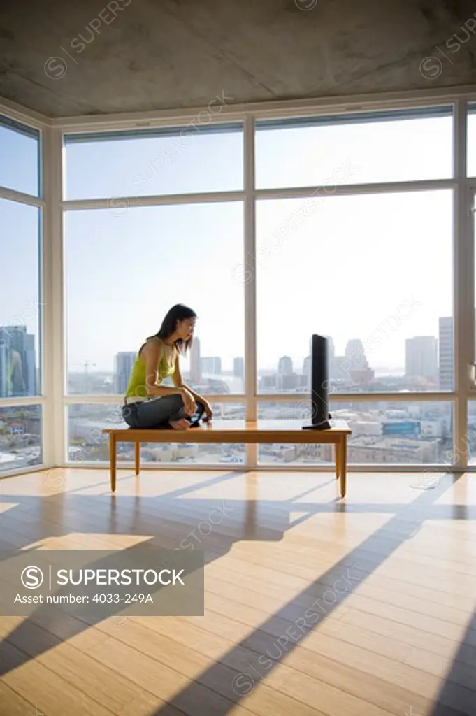 Young woman watching television in a spacious apartment, San Diego, California, USA