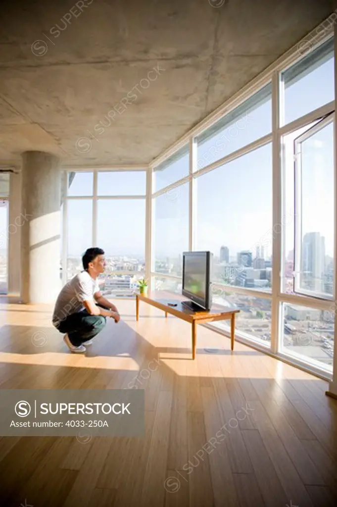 Young man watching television in a spacious apartment, San Diego, California, USA