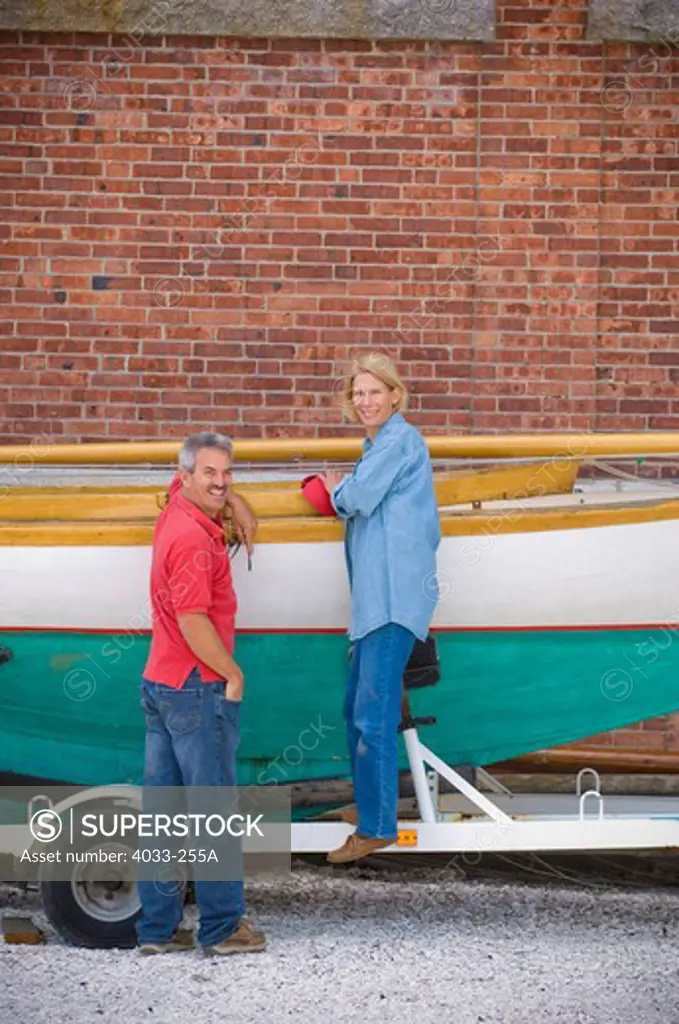 Mid adult couple working on a classic wooden sailboat, Newport, Rhode Island, USA