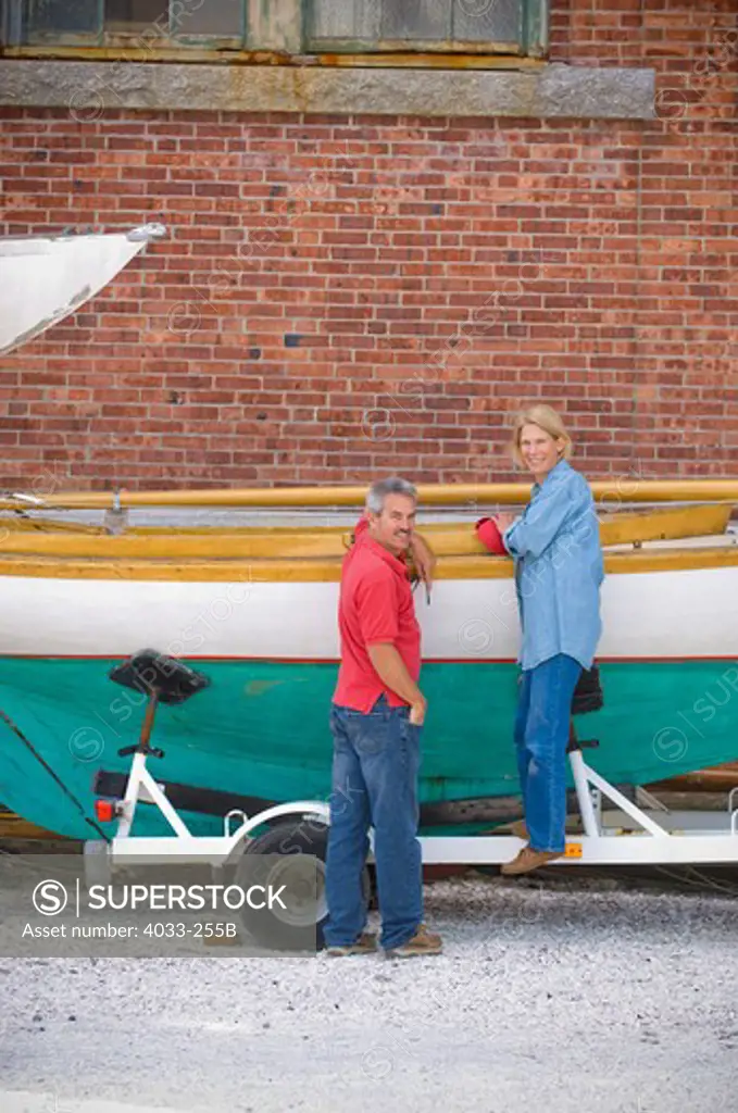 Mid adult couple working on a classic wooden sailboat, Newport, Rhode Island, USA