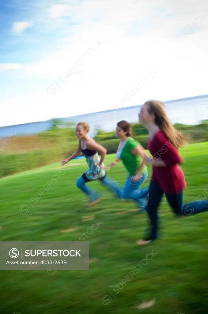 Three young women running on grass, Jamestown, Rhode Island, USA