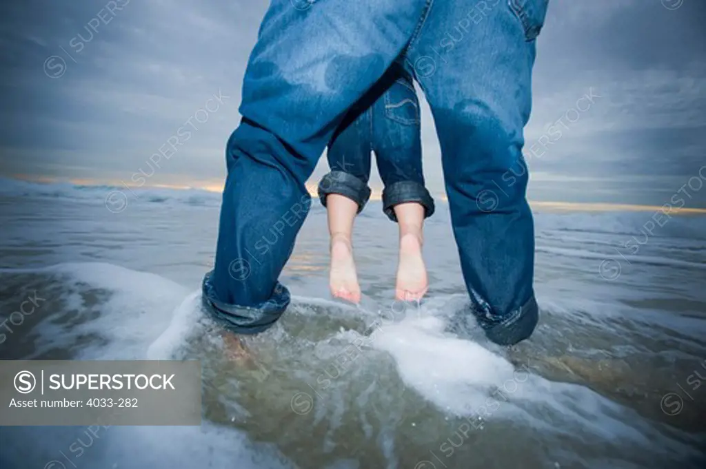 Man swinging his son over water on the beach, La Jolla, California, USA