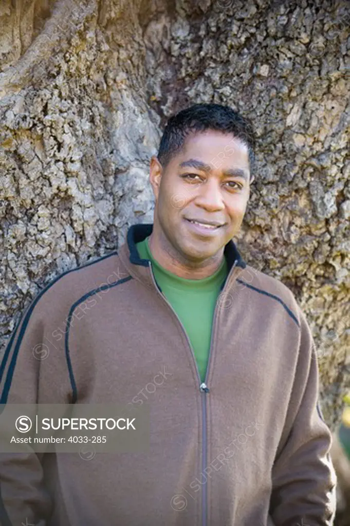 Mid adult man leaning against a tree, San Diego, California, USA