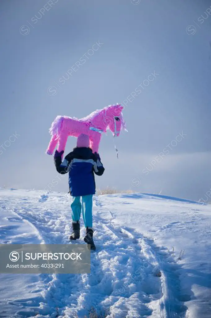 Rear view of a girl carrying a pink pony pinata, Bozeman, Montana, USA