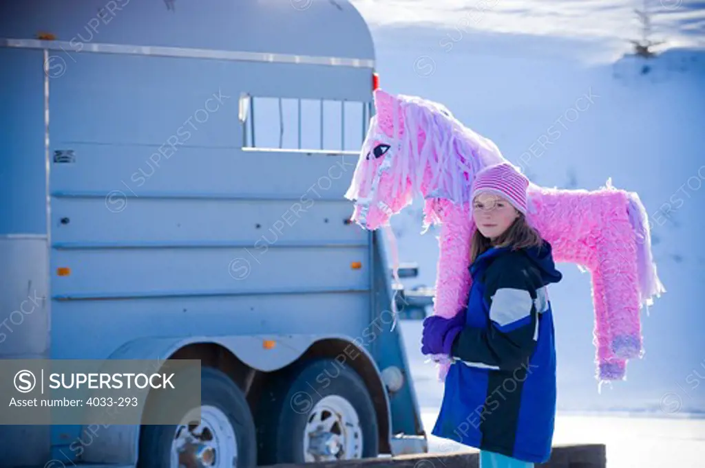 Girl carrying a pink pony pinata, Bozeman, Montana, USA