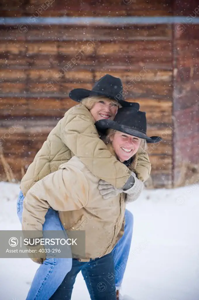 Mature woman riding piggyback on her sister, Bozeman, Montana, USA