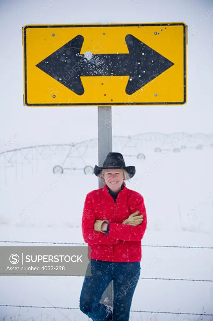 Mature woman leaning against a road sign, Bozeman, Montana, USA