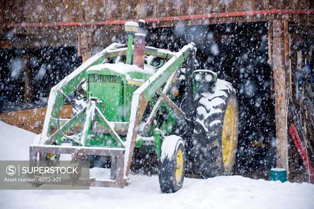 Tractor near a barn during heavy snow, Bozeman, Montana, USA