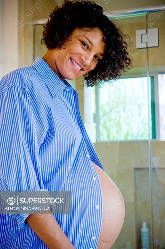 Pregnant woman showing off her abdomen and smiling, San Diego, California, USA