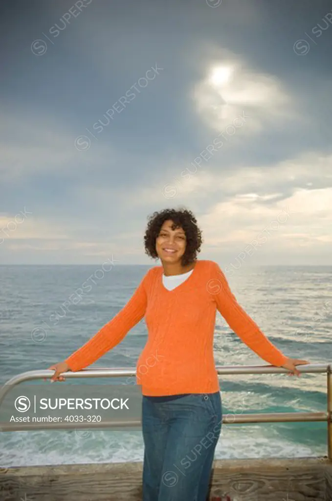 Pregnant woman leaning against a railing on the beach, San Diego, California, USA