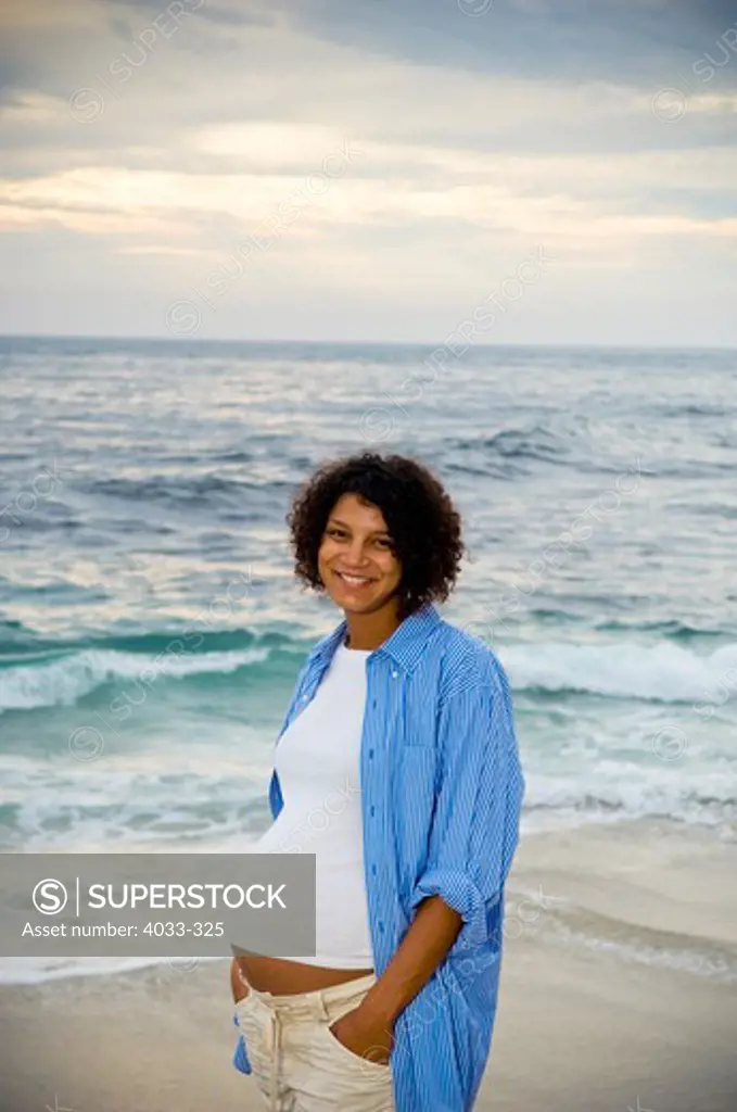 Pregnant woman standing on the beach, San Diego, California, USA