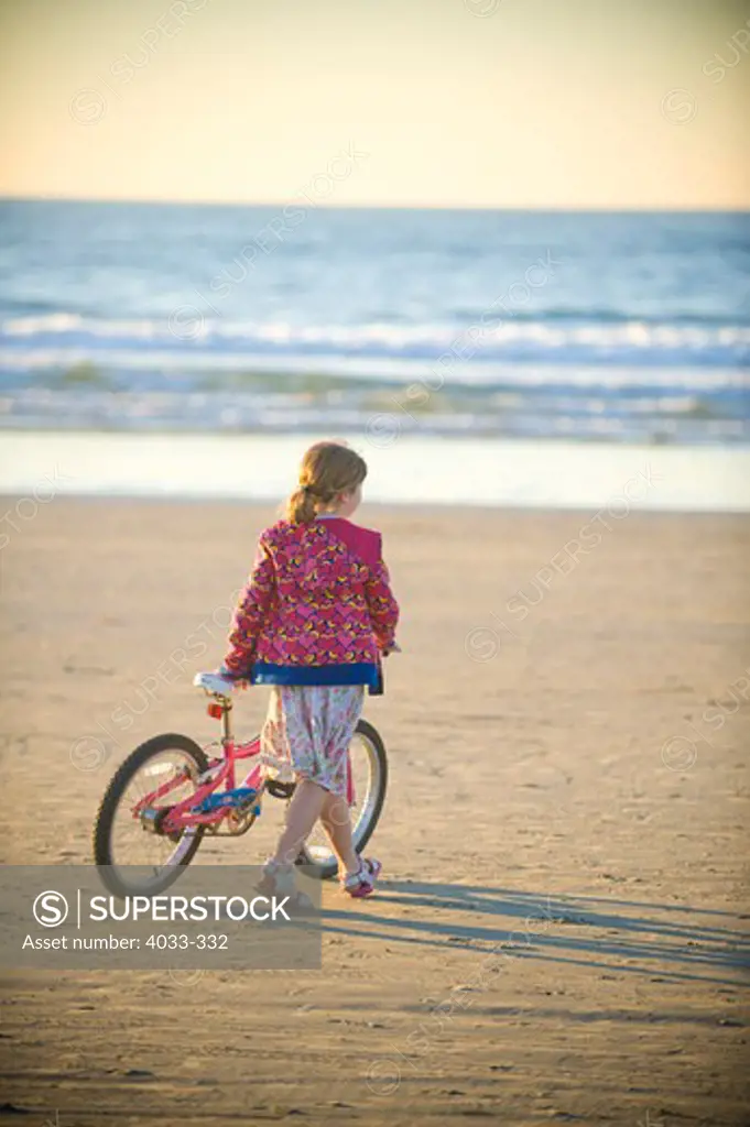 Girl walking with her bicycle on the beach, La Jolla, California, USA