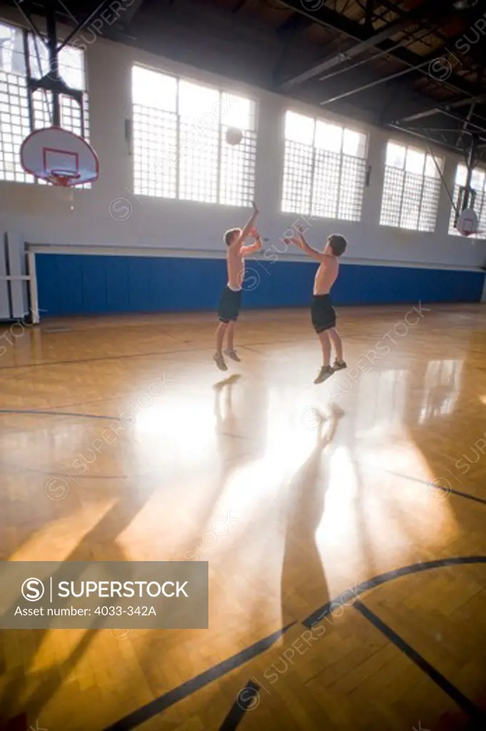 Two boys practicing basketball in a high school gymnasium, Bozeman, Montana, USA