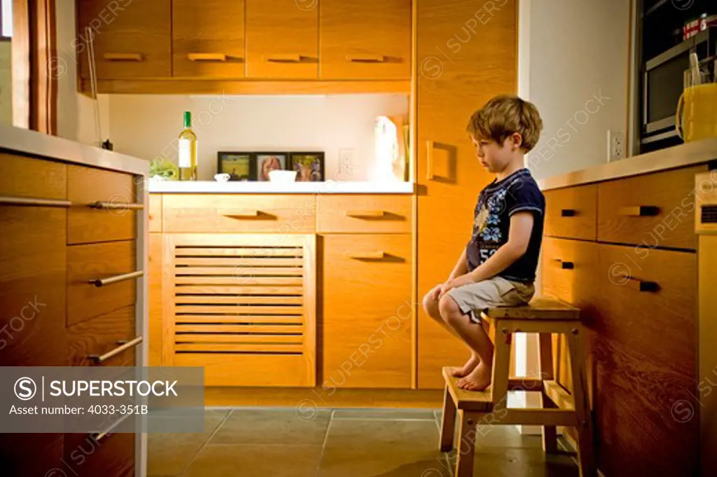 Boy sitting on a stool in the kitchen, La Jolla, California, USA
