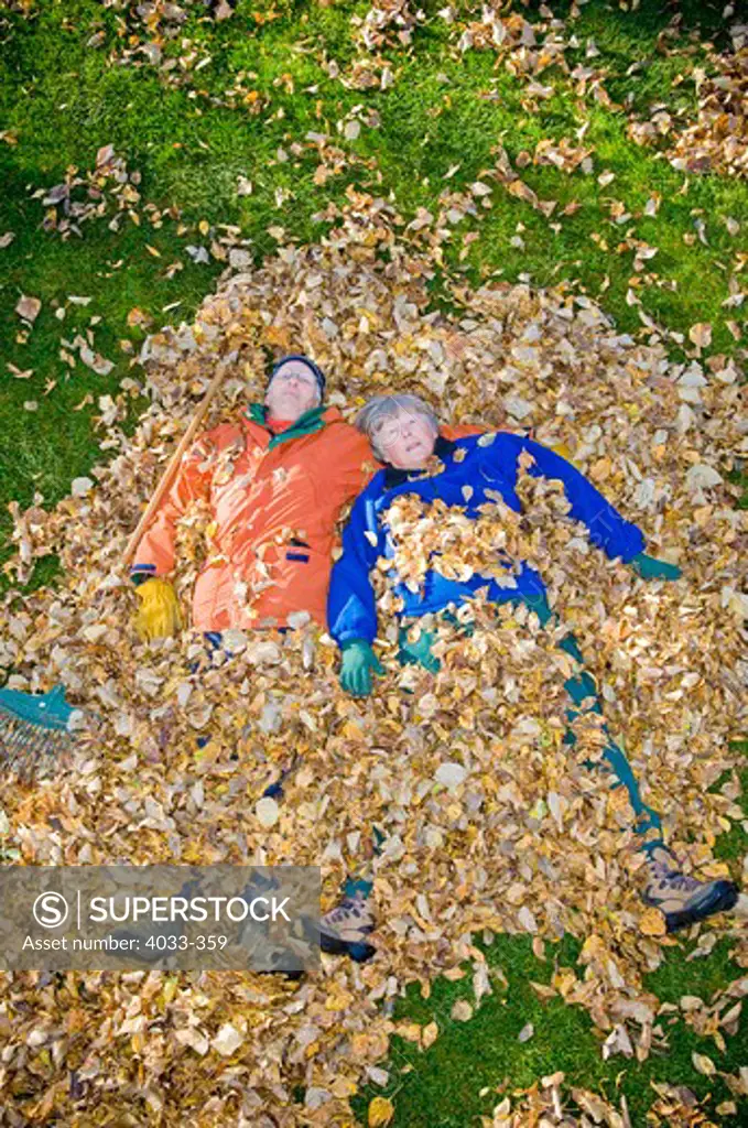 Senior couple lying in heap of leaves, Bozeman, Montana, USA