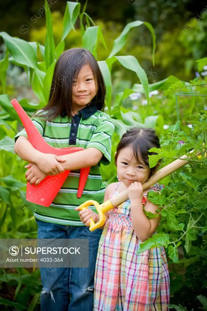 Boy and his sister with gardening equipment, San Diego, California, USA