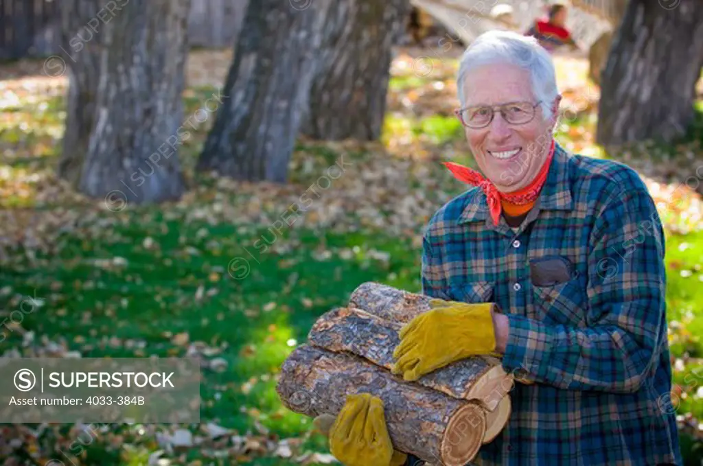 Senior man carrying firewood, Bozeman, Montana, USA